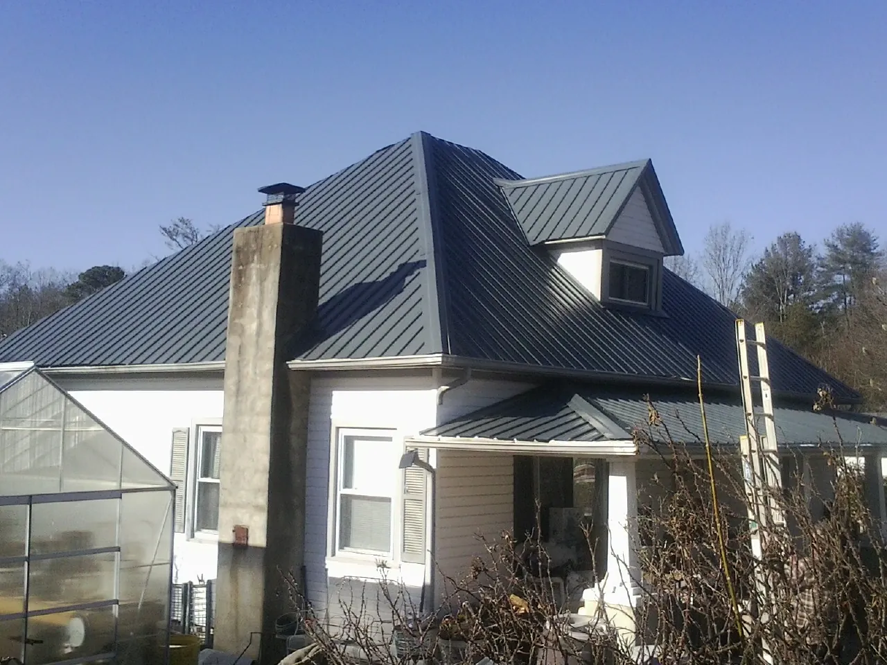 Dark blue standing seam metal roof on a white farmhouse with dormer — Slate & Tile Roof Repair by Roofing Brothers in Eureka
